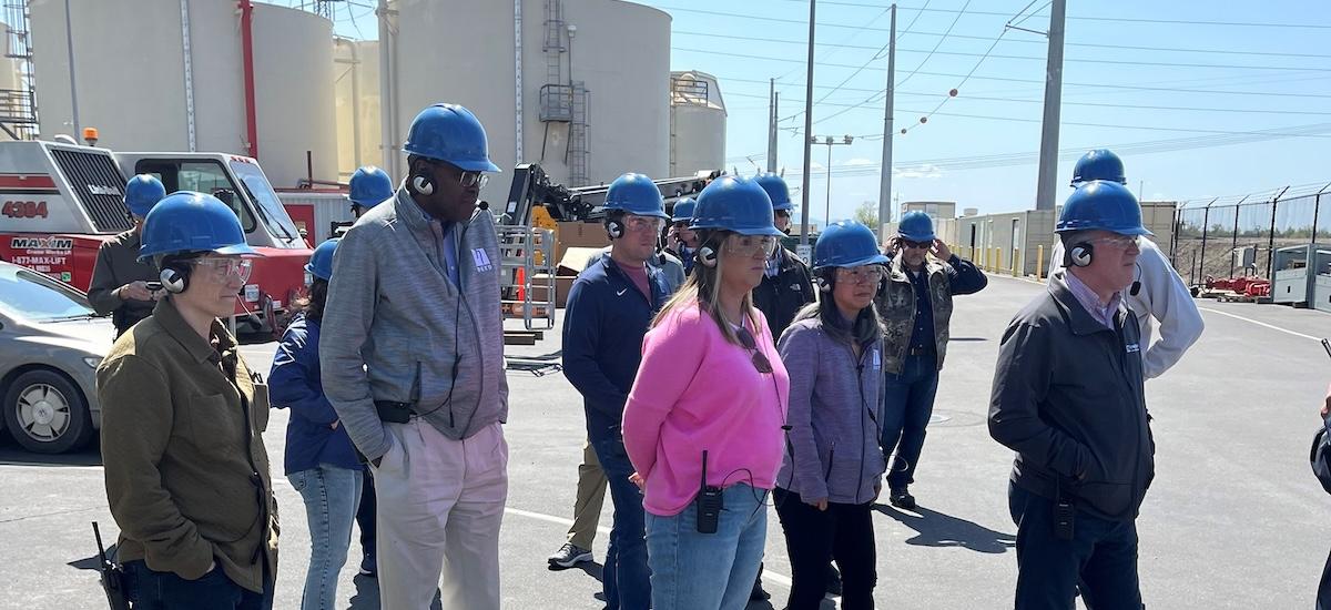 People watching a demonstration while wearing hard hats