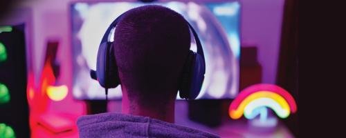 teen wearing headphones sitting at a computer