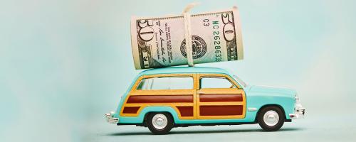 Retro wood paneled station wagon toy with roll of US currency tied on top