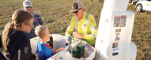 A Lincoln Electric System crew member assists kids in a bucket truck during a community event